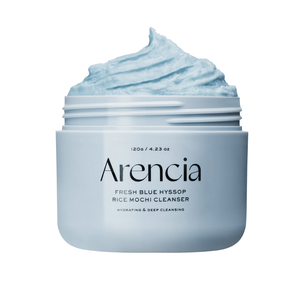 Close-up de um frasco aberto Arencia Fresh Blue Hyssop Rice Mochi Cleanser. O creme de limpeza azul tem uma textura arejada e batida e preenche o topo do frasco.