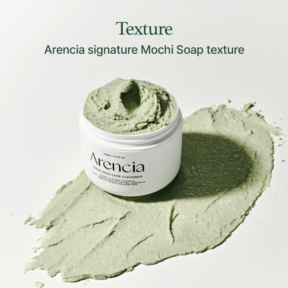 Arencia Fresh Rice Cake Cleanser em frasco aberto com textura cremosa verde semelhante a mochi espalhada ao redor do frasco sobre uma superfície branca.