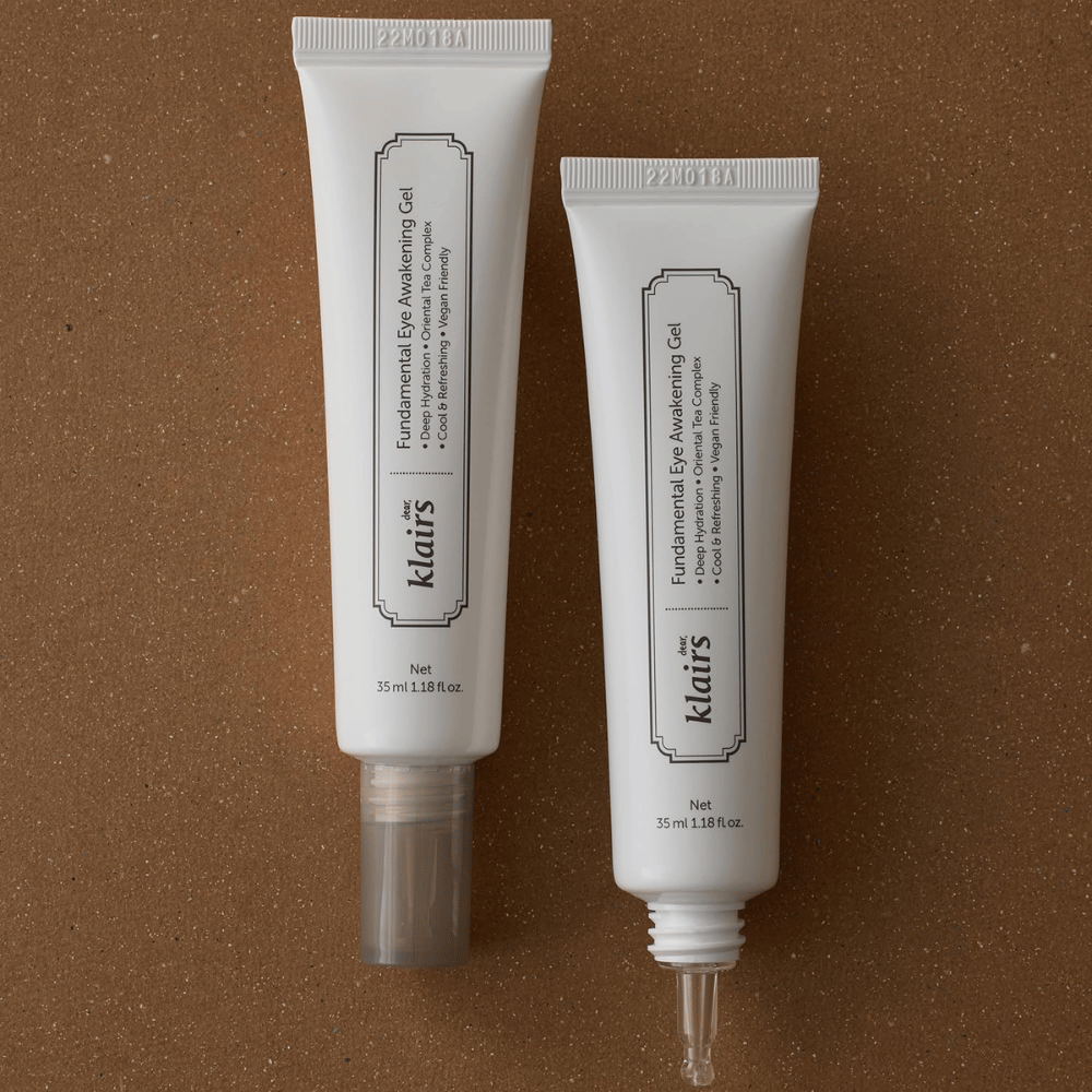 Imagem de produto que mostra Klairs Fundamental Eye Awakening Gel em duas versões – uma bisnaga fechada e uma bisnaga aberta que destaca a ponta aplicadora estreita. A embalagem tem um design branco minimalista e realça o foco do produto na hidratação, na sensação refrescante e no cuidado revitalizante da zona do contorno dos olhos.