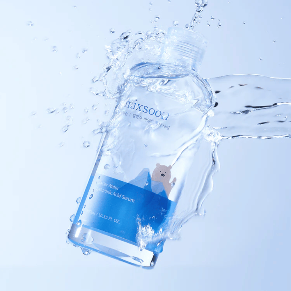 Mixsoon garrafa Glacier Water Hyaluronic Acid Serum com etiqueta azul e motivo de urso polar rodeada por água salpicando contra um fundo azul claro.