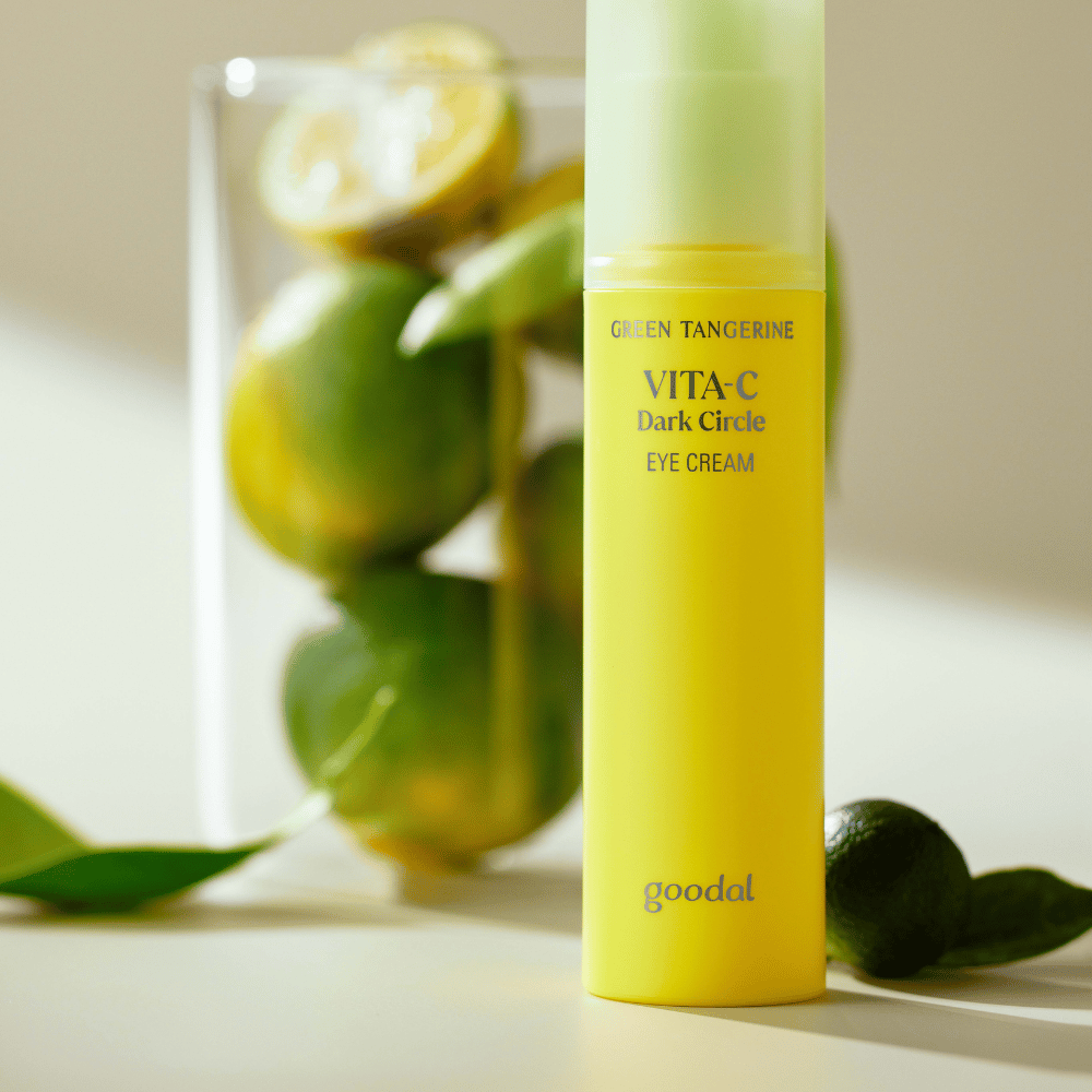 Uma garrafa Goodal Green Tangerine Vita C Dark Circle Eye Cream 30ml em uma mesa ao lado de uma lima.
