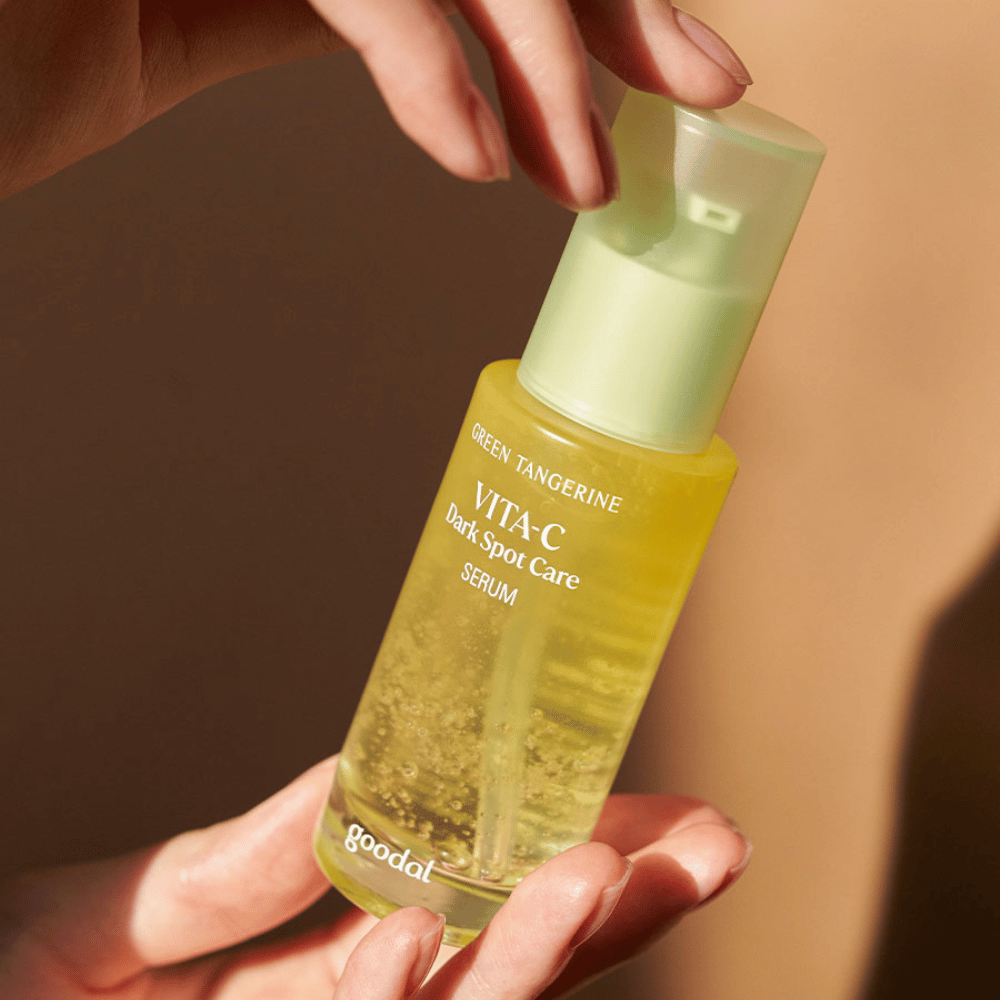 Uma pessoa segurando uma garrafa Green Tangerine Vita C Dark Spot Care Serum 40ml de Goodal para hiperpigmentação e tratamento de manchas escuras.