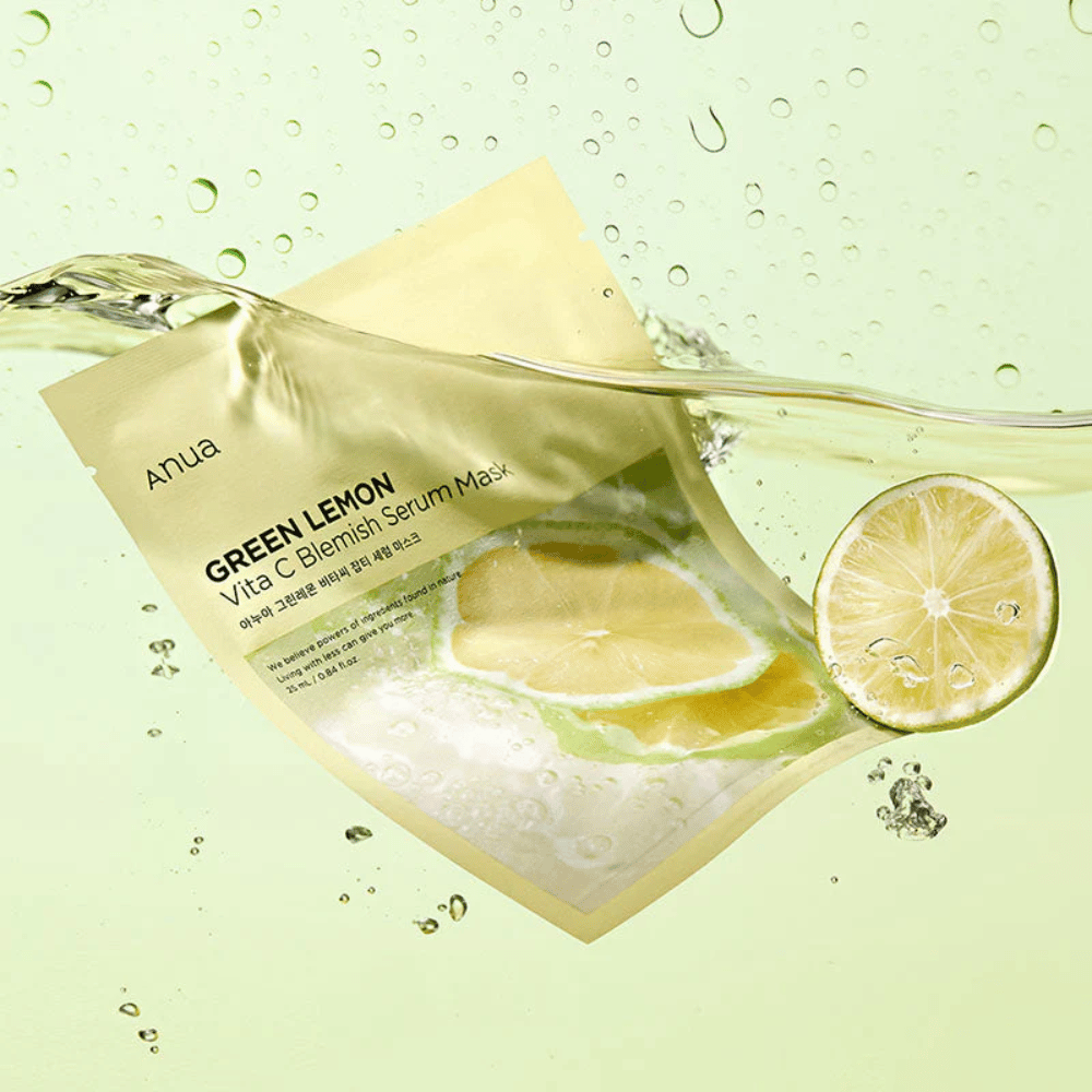 Uma imagem vibrante da embalagem de Anua Green Lemon Vita C Blemish Serum Mask com gotas de água transparentes e fatias de limão verde ao redor. A embalagem está parcialmente coberta por um fluxo de água sobre um fundo verde claro.