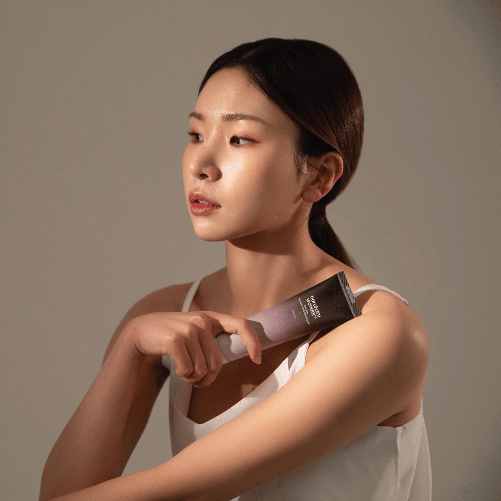 Uma jovem asiática segurando uma escova na mão enquanto usa Haruharu Wonders Black Rice Moisture 5.5 Soft Cleansing Gel 100ml.