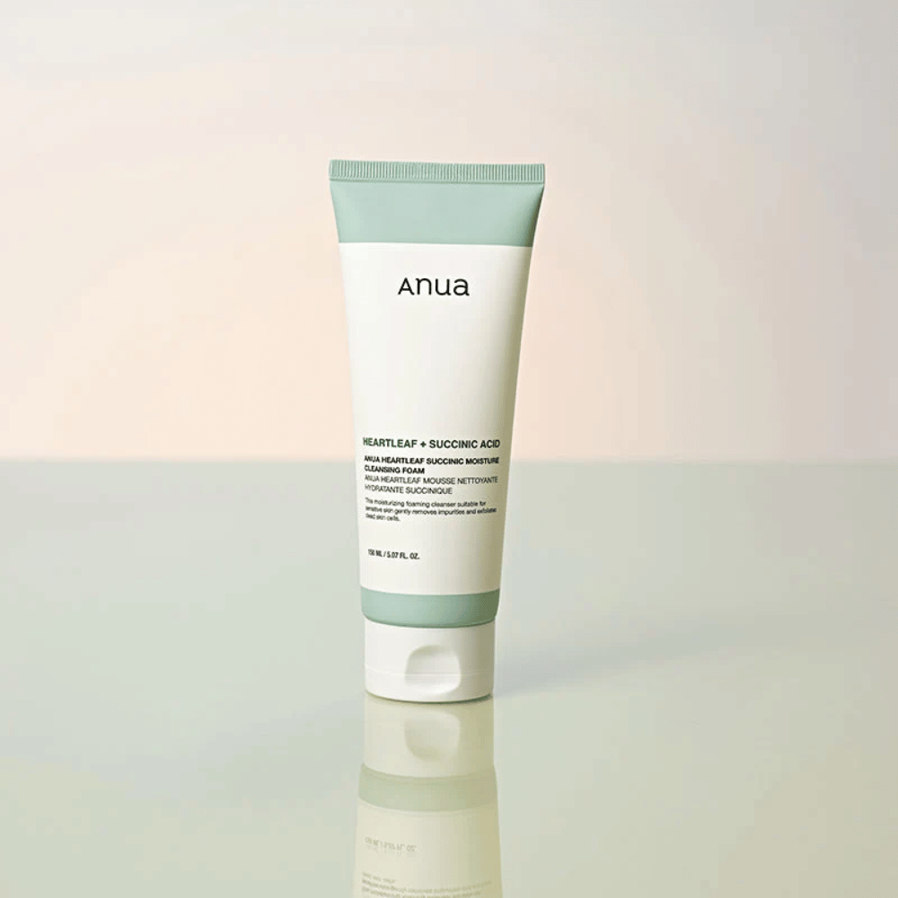 Imagem de produto isolada de Anua Heartleaf + Succinic Acid Moisture Cleansing Foam. O produto é apresentado na vertical sobre uma superfície refletora que destaca claramente o design da embalagem e a estética elegante da marca.
