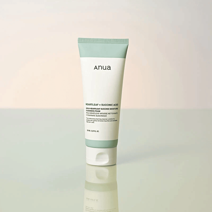 Imagem de produto isolada de Anua Heartleaf + Succinic Acid Moisture Cleansing Foam. O produto é apresentado na vertical sobre uma superfície refletora que destaca claramente o design da embalagem e a estética elegante da marca.
