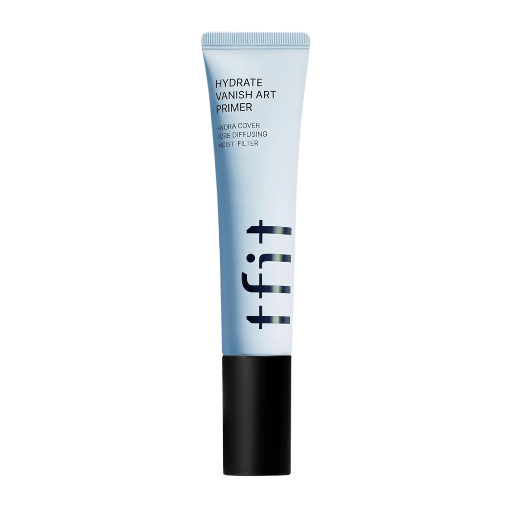 Tubo azul com tampa preta de TFIT, marcado como "Hydrate Vanish Art Primer" – um primer hidratante com efeito suavizante de poros e tecnologia de filtro de umidade.
