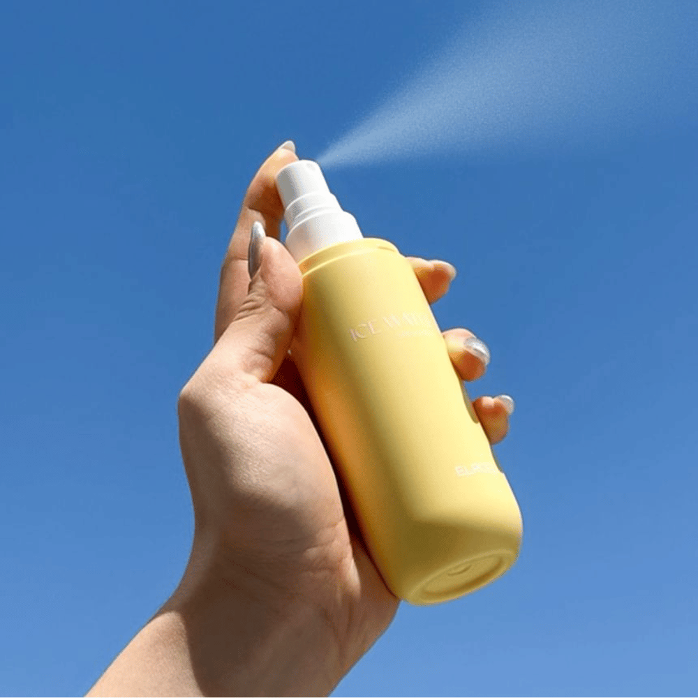 ELROEL Ice Water Sun Mist SPF 40 PA+++ bruma solar pulverizada do frasco contra um céu azul, proteção solar leve que hidrata e refresca a pele