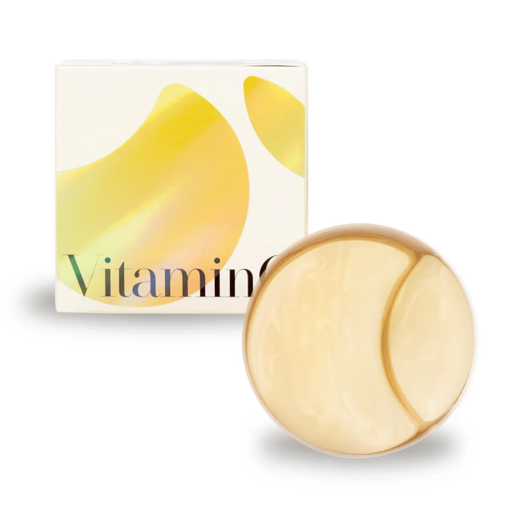 K-Secret Extra Illuminating Eye Gel Patches com vitamina C em hidrogel dourado, frasco e embalagem ao fundo.