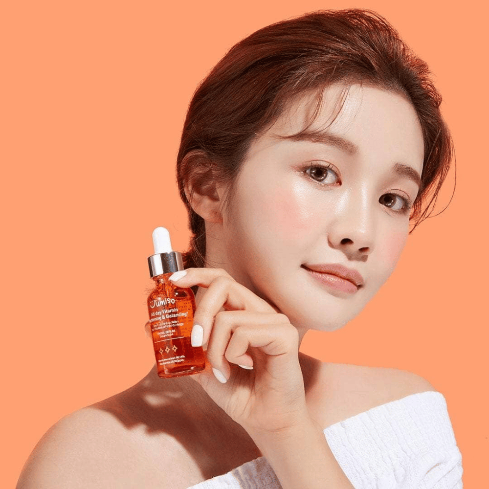 Uma mulher segurando uma garrafa de JUMISO All Day Vitamin Brightening & Balancing Facial Serum 30ml.