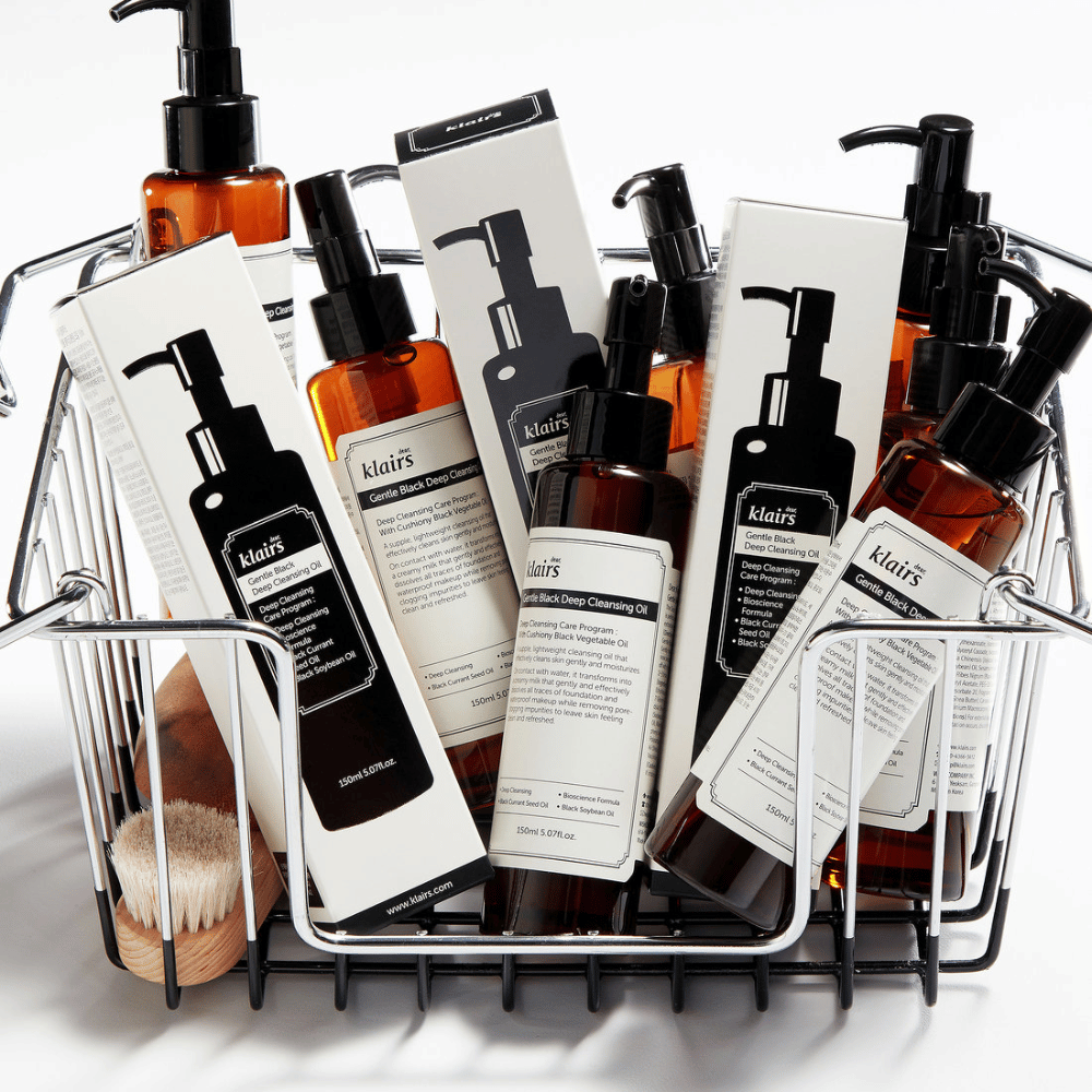 Um mini carrinho de compras cheio de produtos de cuidados com a pele da Klairs, incluindo Gentle Black Deep Cleansing Oil em garrafas transparentes com bombas pretas e embalagens correspondentes.