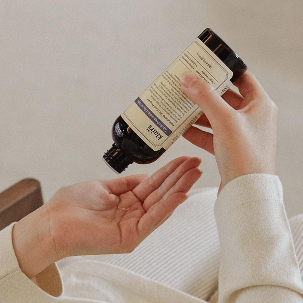 Uma pessoa segurando uma garrafa de Klairs Supple Preparation Facial Toner de cabeça para baixo sobre sua mão, pronta para dosar o produto.