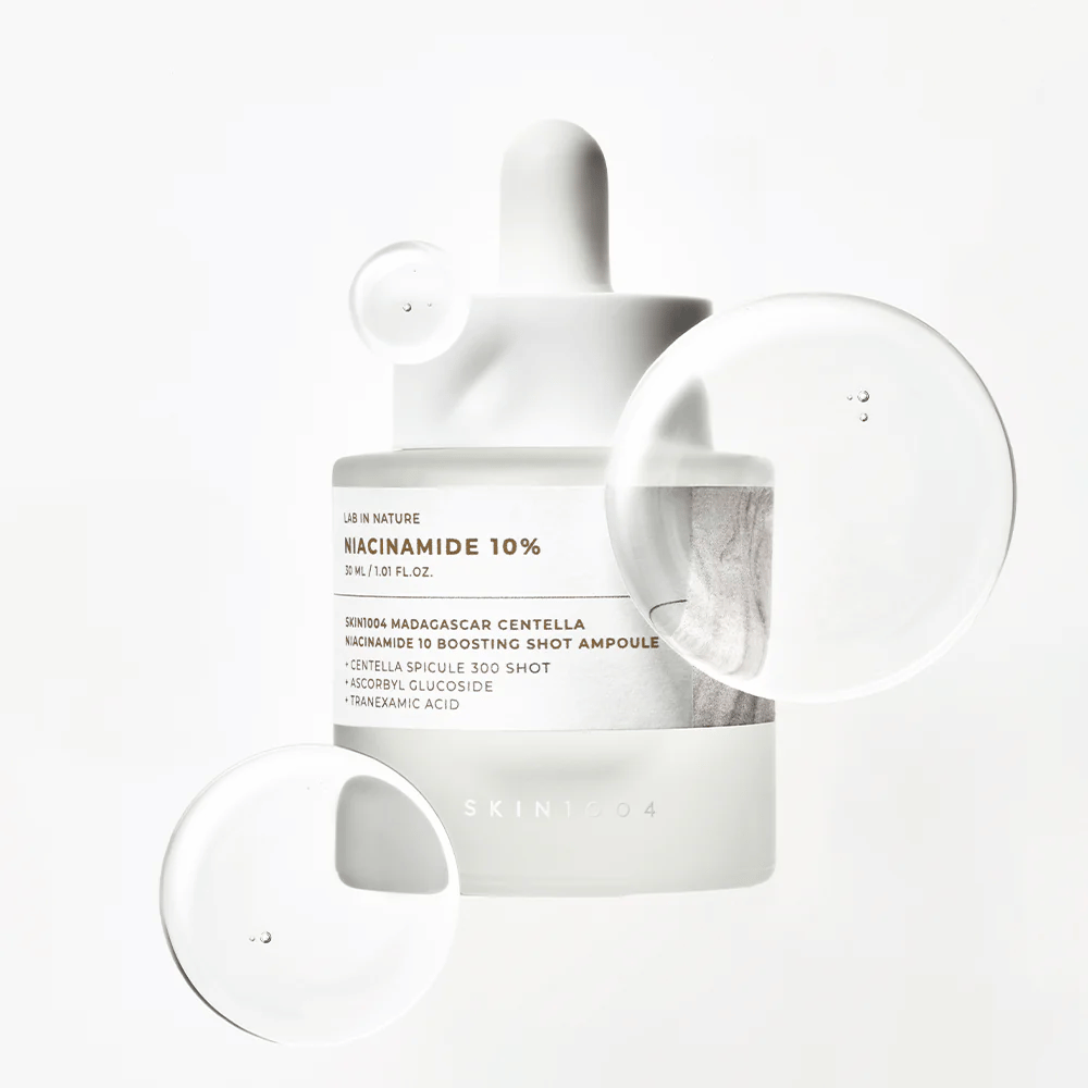 SKIN1004 Madagascar Centella Niacinamide 10 Boosting Shot Ampoule com gotas de sérum que mostram uma fórmula leve, de rápida absorção com niacinamida, ácido tranexâmico e centella.