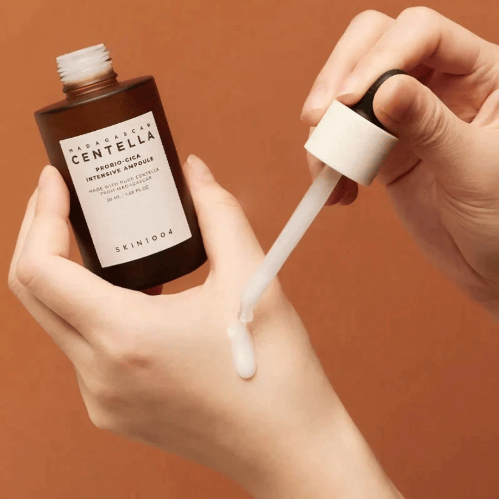 Mãos usando conta-gotas para dosar "Madagascar Centella Probio-Cica Intensive Ampoule" de SKIN1004.