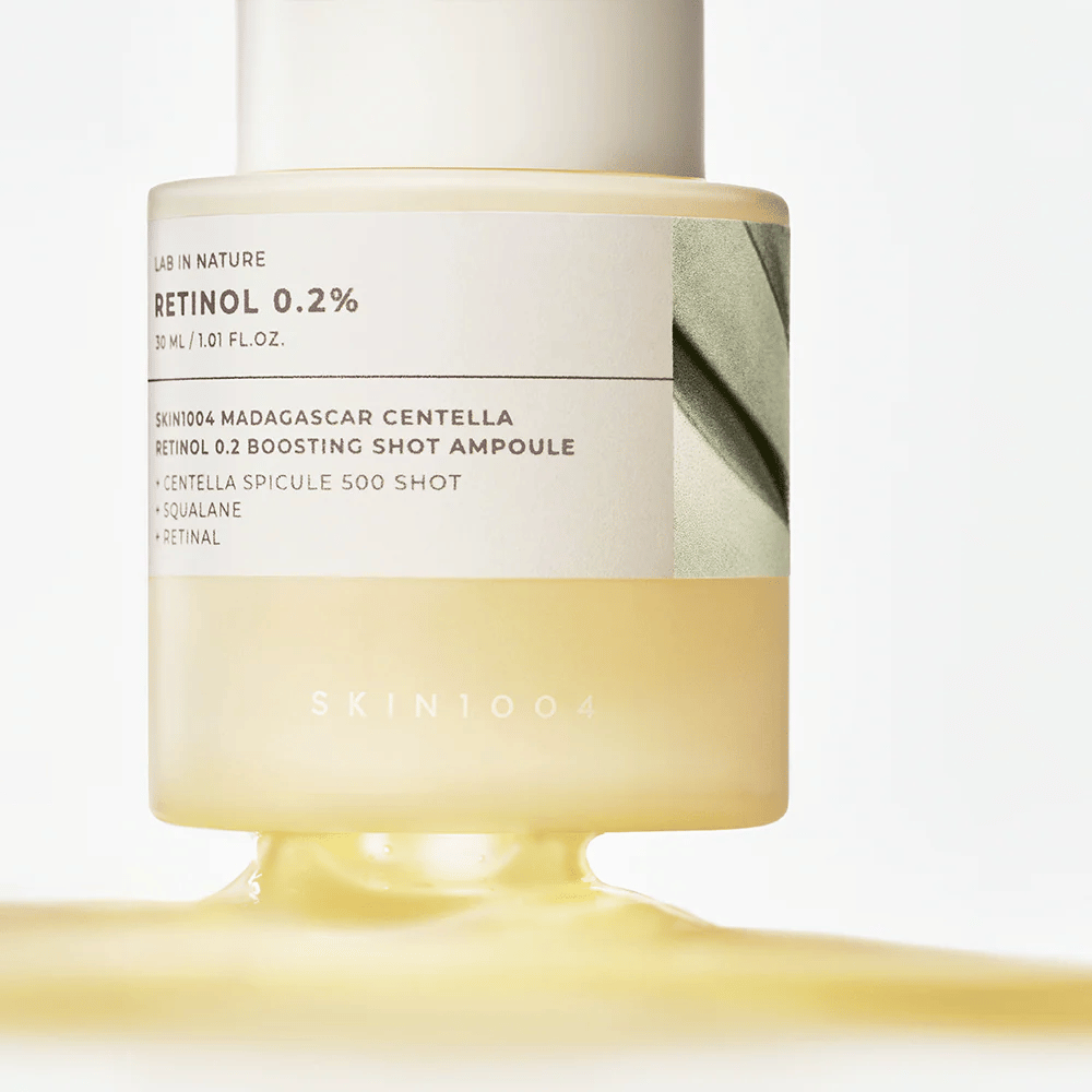 Close-up de SKIN1004 Madagascar Centella Retinol 0.2 Boosting Shot Ampoule mostrando a textura levemente amarela e sedosa do soro de retinol para renovação noturna da pele.