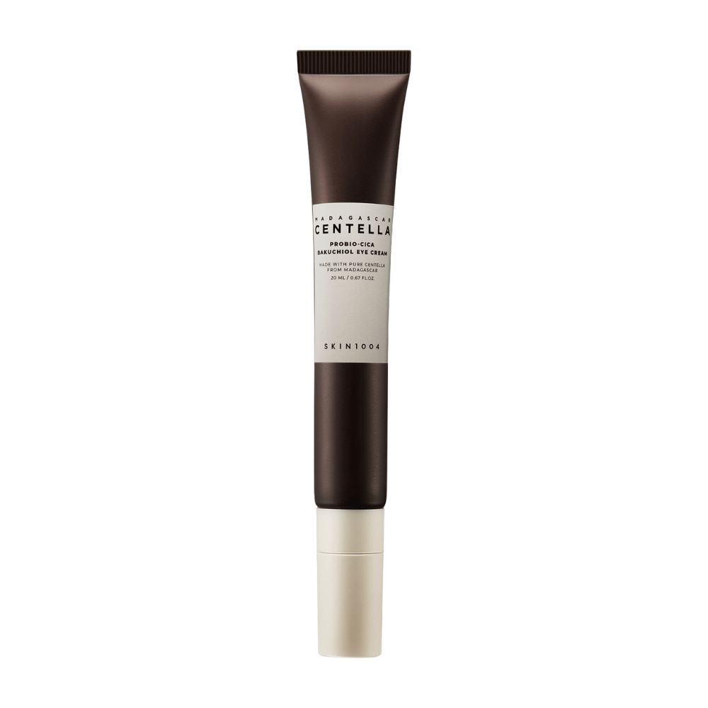 Um tubo de "Madagascar Centella Probio-Cica Bakuchiol Eye Cream" de SKIN1004. O produto é projetado para a área dos olhos e contém ingredientes como centella de Madagascar e bakuchiol, conhecidos por suas propriedades de cuidado e hidratação da pele. O tubo é elegante com uma cor marrom escuro que transita para o branco.