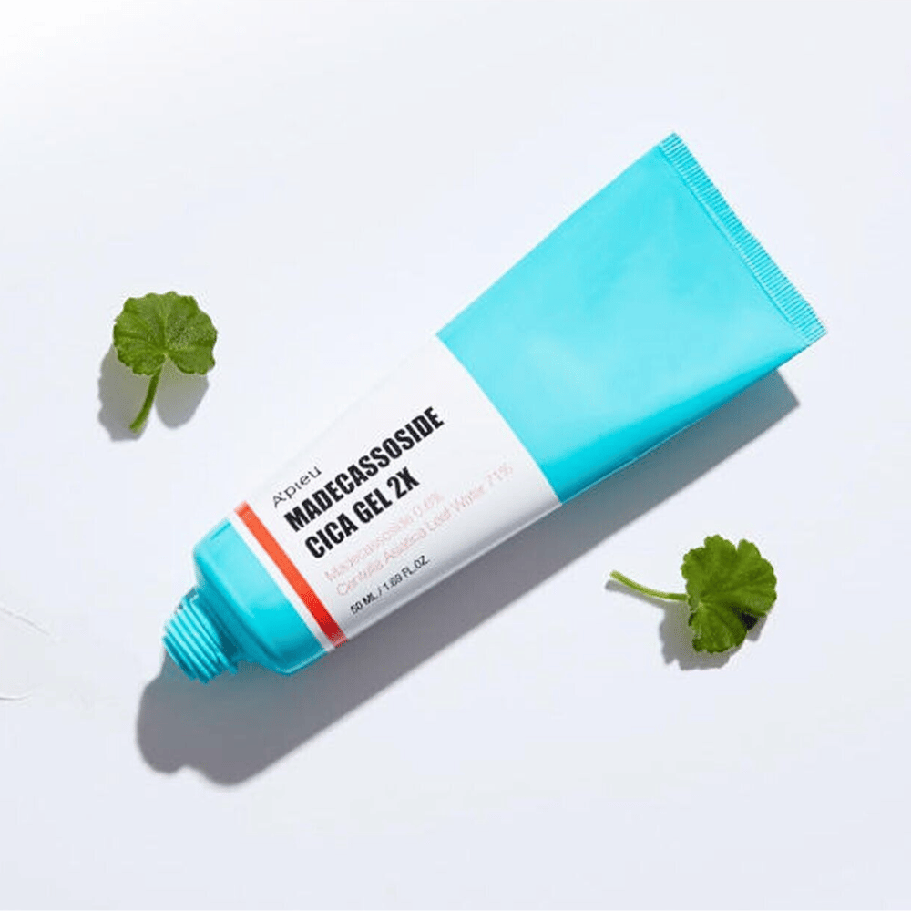 A’pieu Madecassoside Cica Gel 2X em tubo azul com etiqueta branca, cercado por três folhas verdes de centella asiatica em fundo branco.