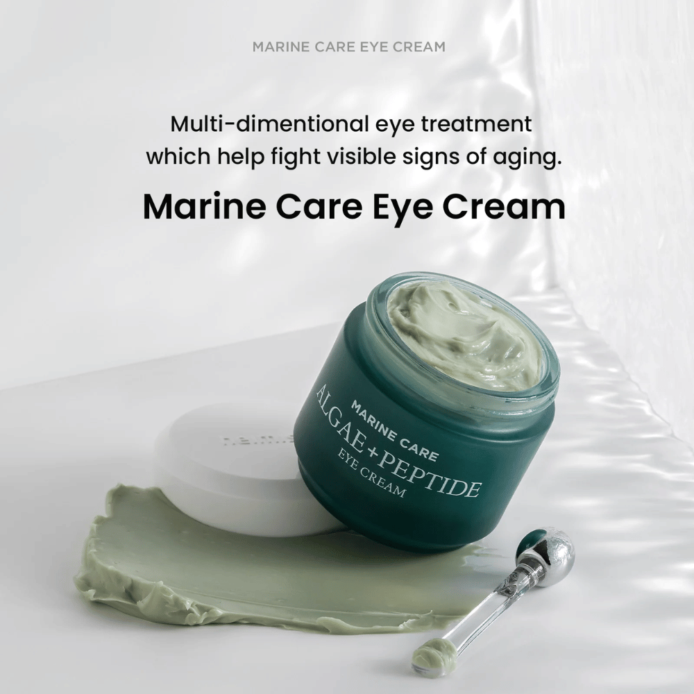 Heimish Marine Care Algae + Peptide Eye Cream em um pote aberto com creme esverdeado. O creme está espalhado ao lado do pote e um aplicador está ao lado. O produto combate sinais de envelhecimento e proporciona hidratação intensa.