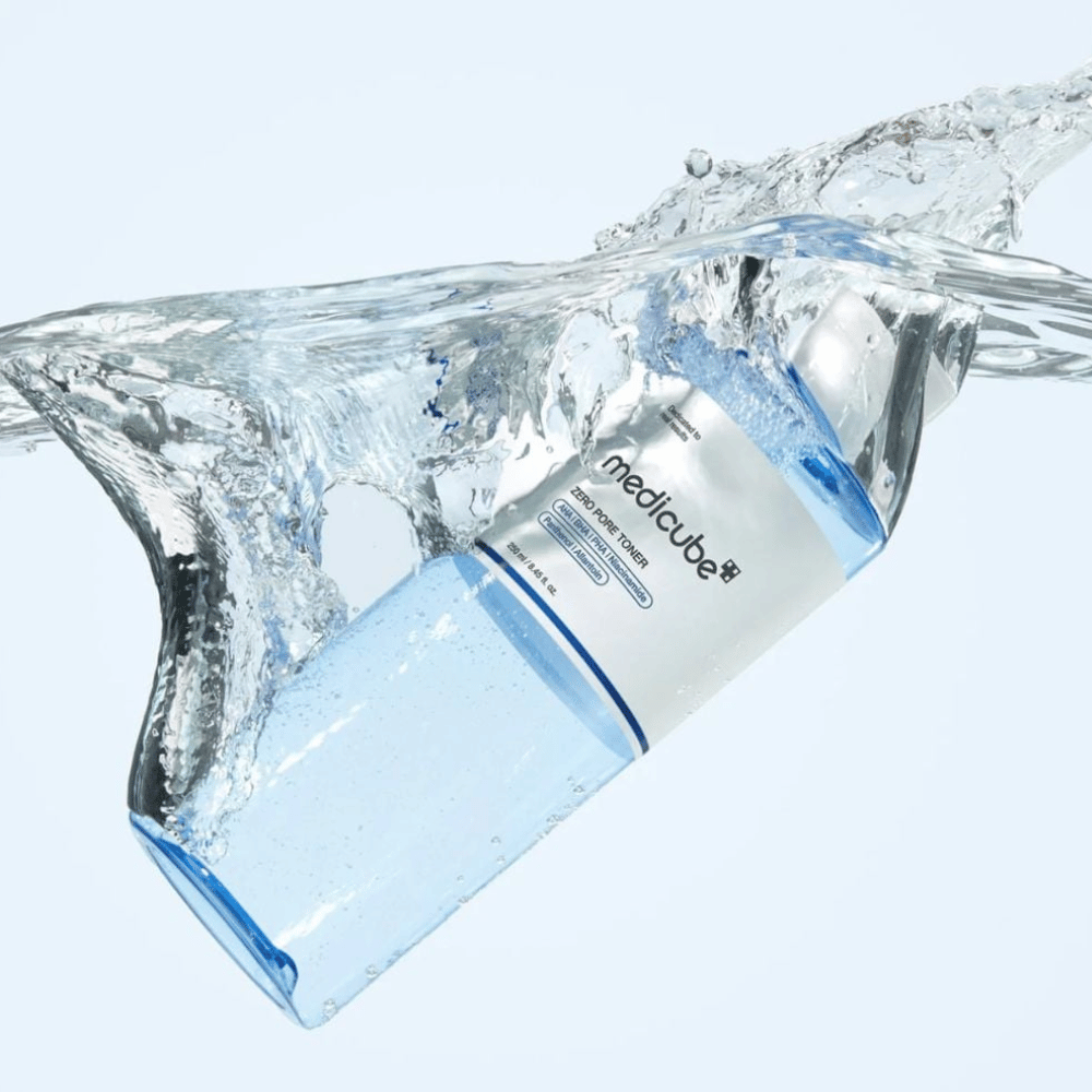 Medicube Zero Pore Toner 250 ml, tónico esfoliante com AHA, BHA e PHA. Garrafa azul transparente rodeada por um grande salpico de água.