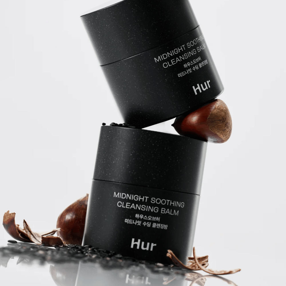 Duas embalagens de Como Midnight Soothing Cleansing Balm empilhadas com ingredientes naturais. Bálsamo de limpeza nutritivo para limpeza diária de pele sensível.
