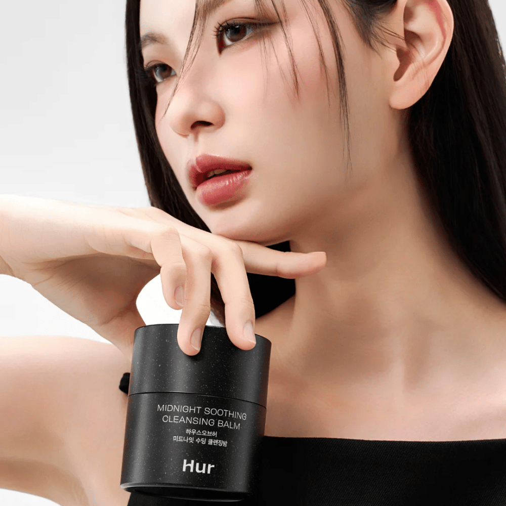 Modelo segurando Como Midnight Soothing Cleansing Balm. Bálsamo de limpeza coreano que remove eficazmente a maquiagem e limpa a pele sem irritação.