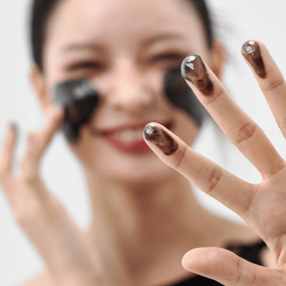 Modelo aplicando Como Midnight Soothing Cleansing Balm na pele. Bálsamo de limpeza cremoso que limpa profundamente e deixa a pele macia e equilibrada.