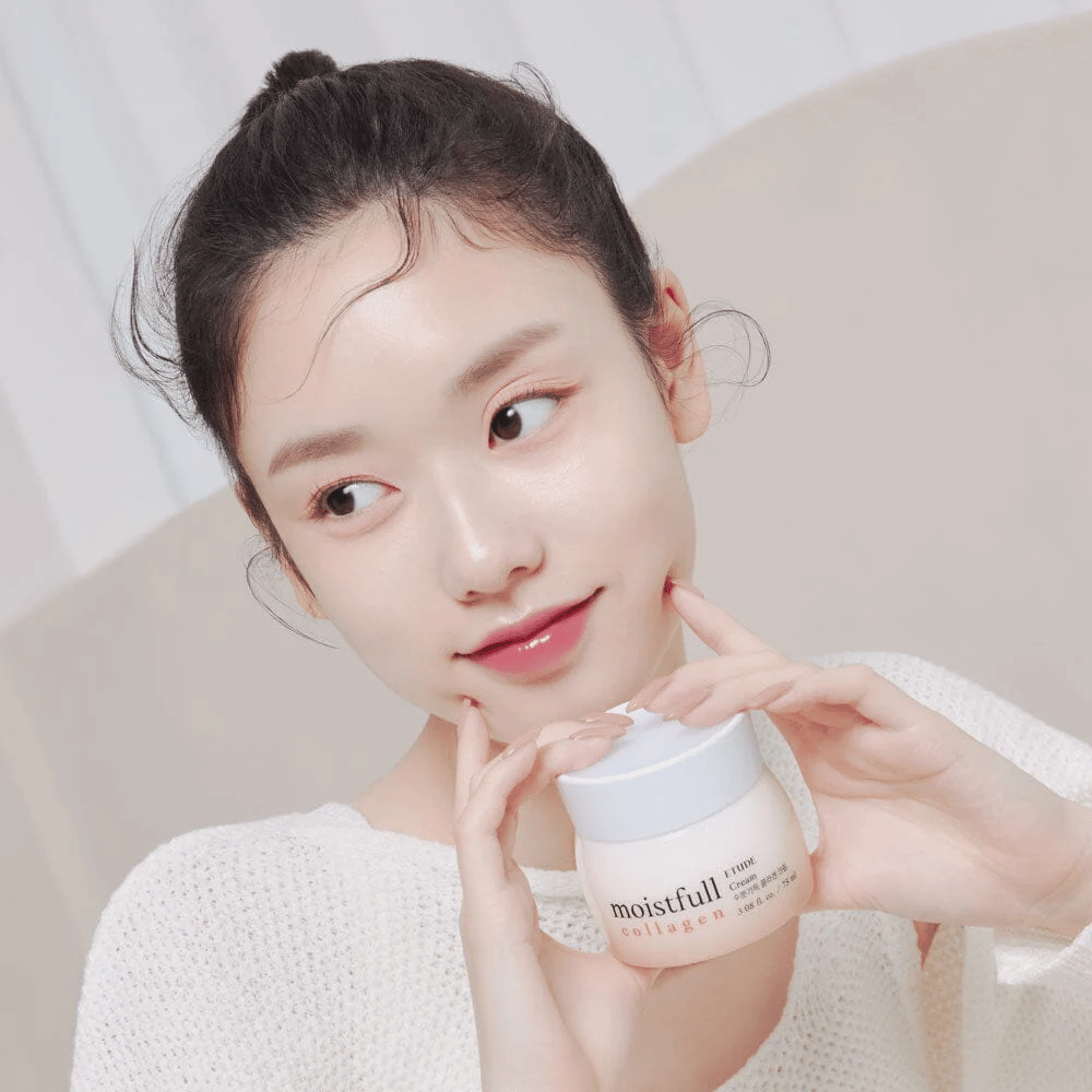 Mulher segura um frasco "Moistfull Collagen Cream", camisola branca, sorrindo.