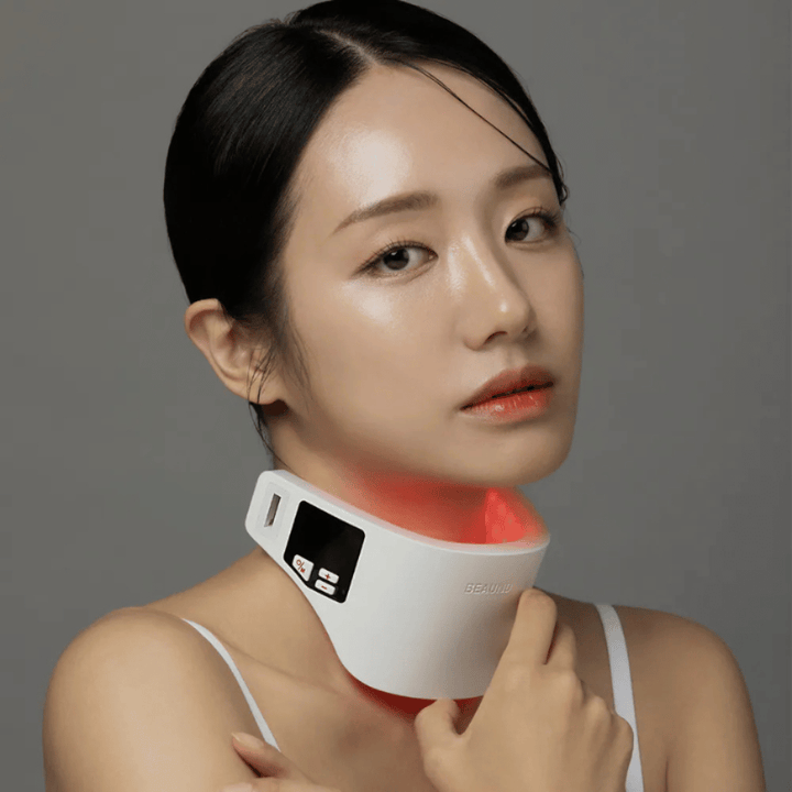 Modelo a usar Beaund Neckcera à volta do pescoço. A iluminação LED vermelha ilustra o tratamento ativo enquanto o dispositivo assenta confortavelmente sobre a pele.