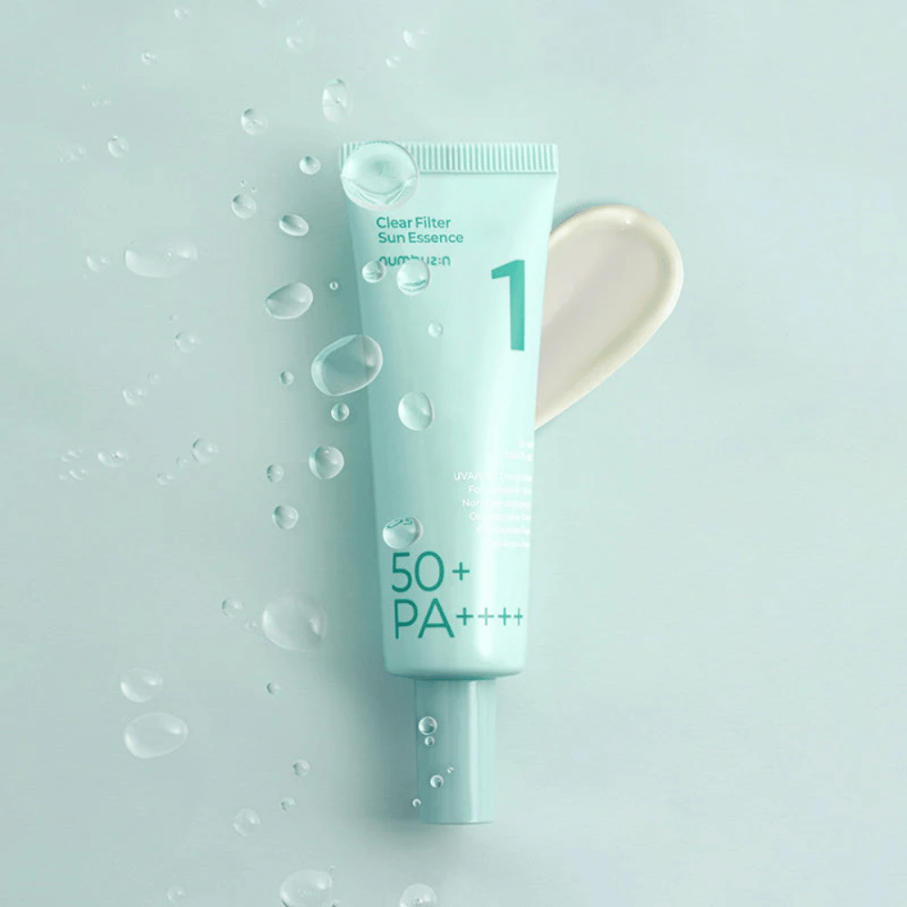 Um tubo azul-claro com No.1 Clear Filter Sun Essence SPF 50+ PA++++. O tubo é decorado com gotas de água e uma porção do produto é mostrada ao lado. O produto é projetado para oferecer alta proteção solar e proteção contra raios UVA/UVB.