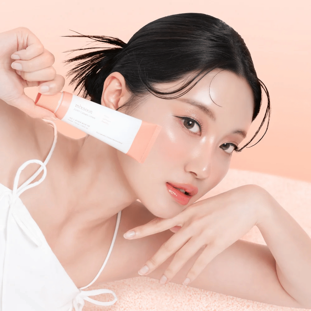 Pessoa com pele radiante segurando Mixsoon PDRN Collagen Cream perto da bochecha. O creme hidrata, fortalece a elasticidade e proporciona um brilho saudável.