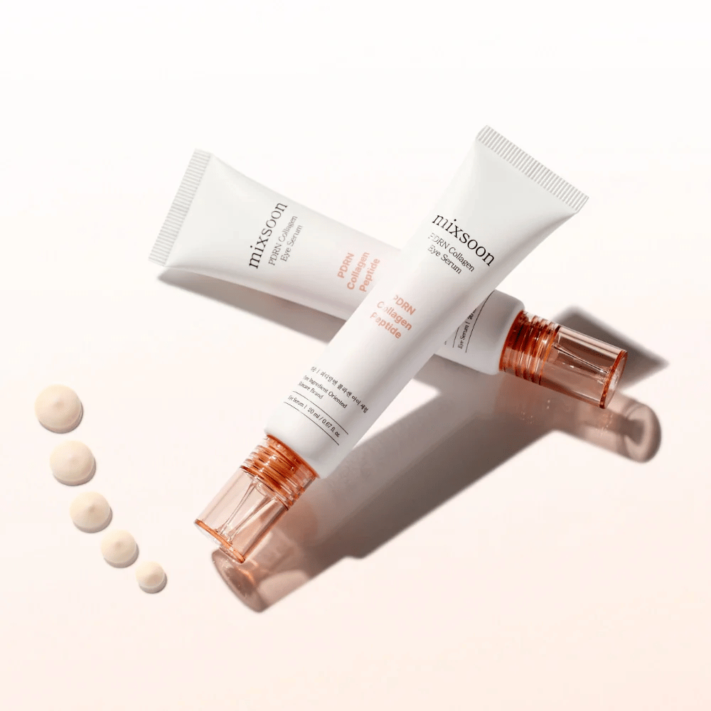 Duas tubas de Mixsoon PDRN Collagen Eye Serum estão cruzadas com pequenas gotas do sérum. Um tratamento leve para os olhos que hidrata e suaviza as linhas.