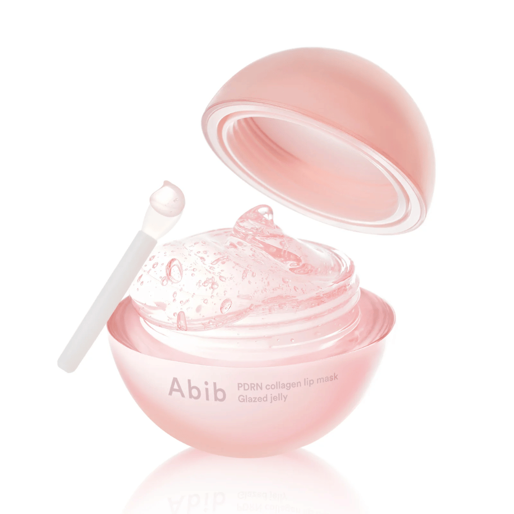 Lata redonda rosa com Abib PDRN Collagen Lip Mask Glazed Jelly, aberta com a tampa inclinada para trás. Gel transparente com bolhas de ar visível na lata junto com uma pequena espátula.