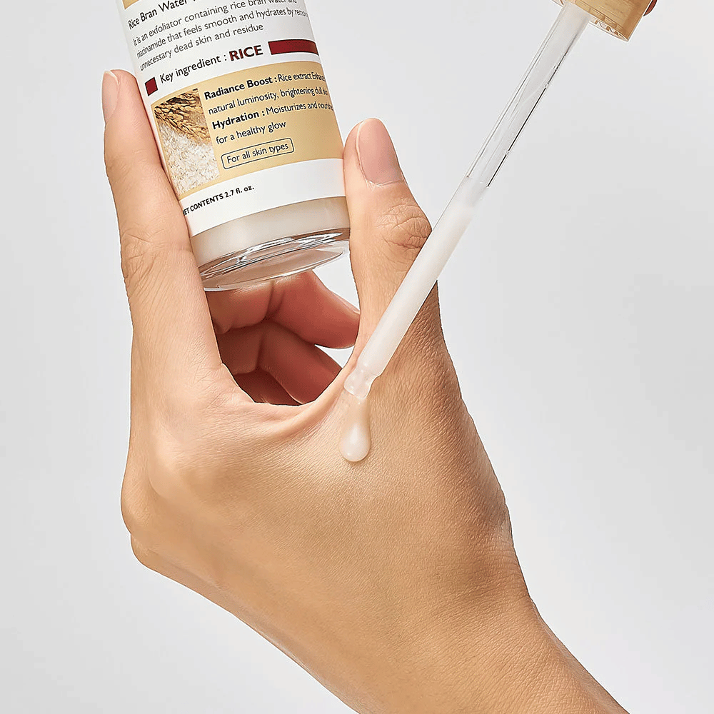 Close-up de Dr.Melaxin Peel Shot Rice Ampoule aplicada com pipeta na mão, ampola esfoliante leve que é rapidamente absorvida e proporciona pele hidratada e lisa.