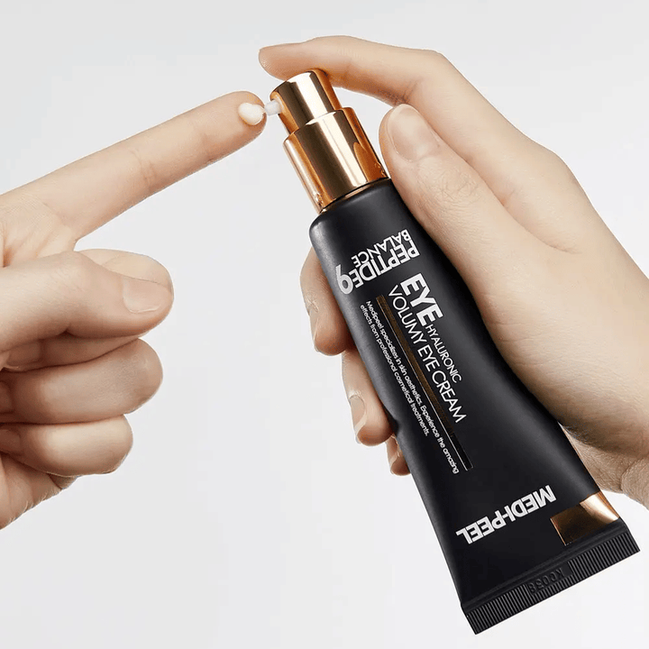 Aplicação de MEDI-PEEL Peptide 9 Hyaluronic Volumy Eye Cream na ponta dos dedos – creme de olhos hidratante com complexo de peptídeos que ajuda a reduzir linhas finas e proporciona uma pele volumosa.