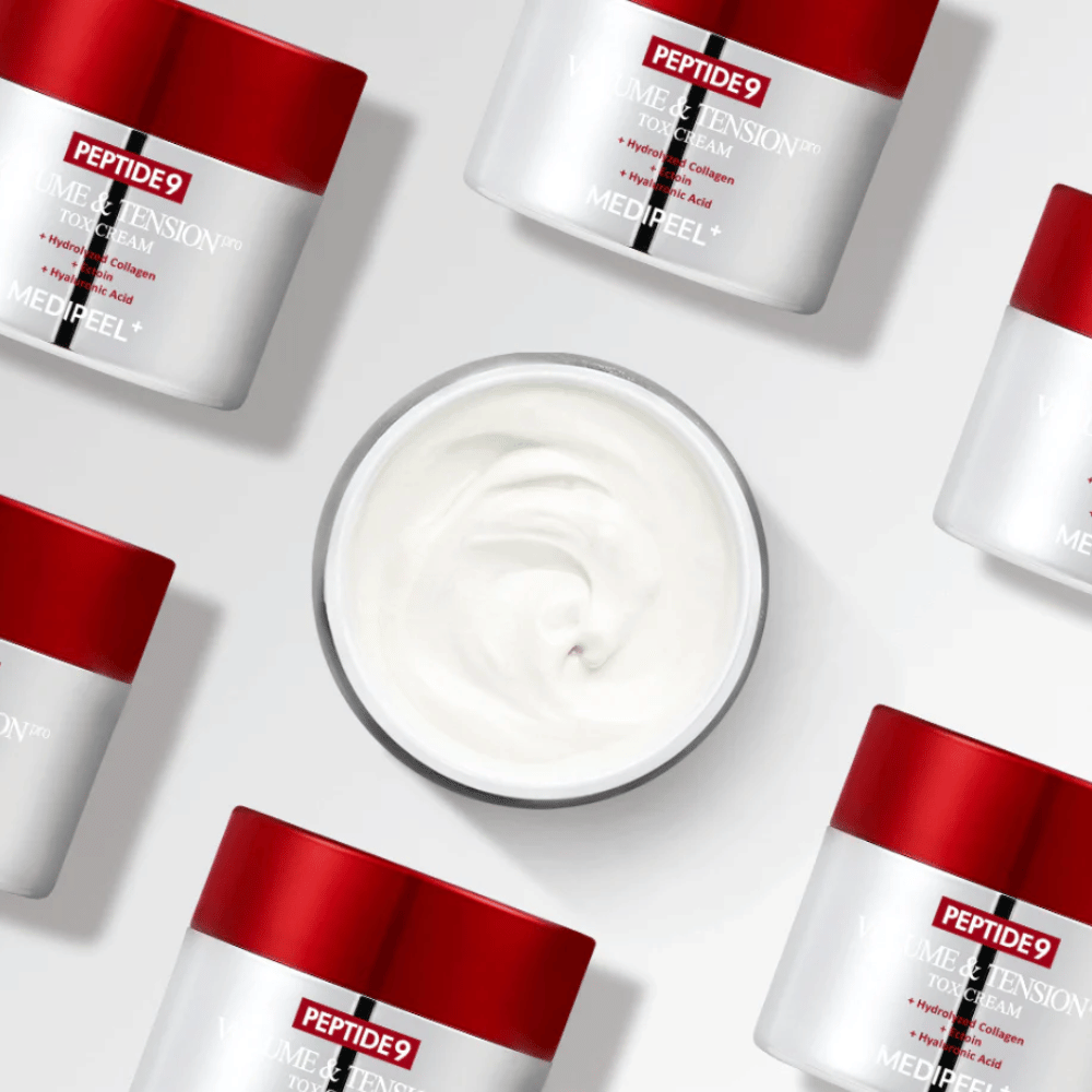 Vários potes de MEDI-PEEL Peptide 9 Volume & Tension Tox Cream dispostos contra um fundo branco. O produto hidrata intensamente e dá volume e brilho à pele.