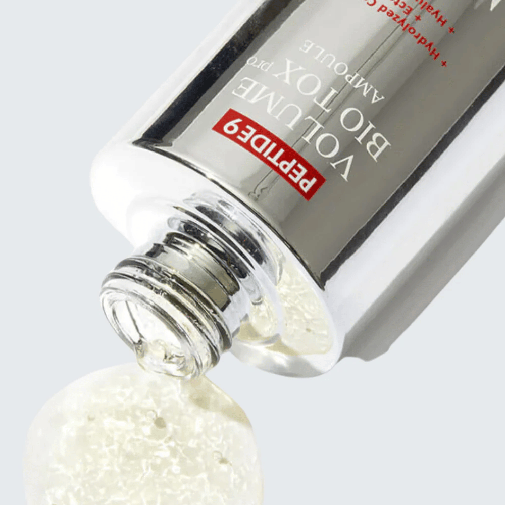 Close-up do MEDI-PEEL Peptide 9 Volume Bio Tox Pro Ampoule sendo derramado. A fórmula clara com colágeno, ectoína e ácido hialurônico hidrata profundamente.