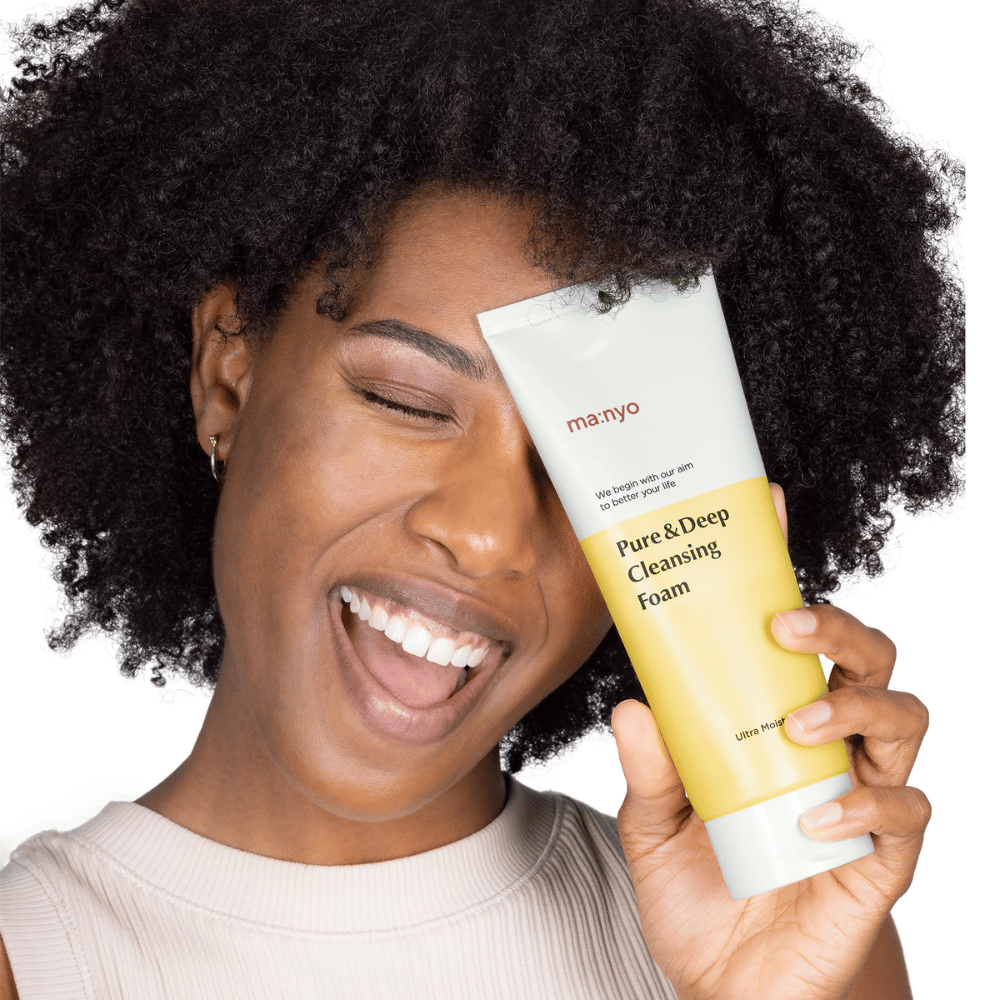 Mulher com cabelo encaracolado segurando Ma:nyo Pure & Deep Cleansing Foam – uma limpeza coreana suave que remove eficazmente a sujeira e a maquiagem sem ressecar a pele.