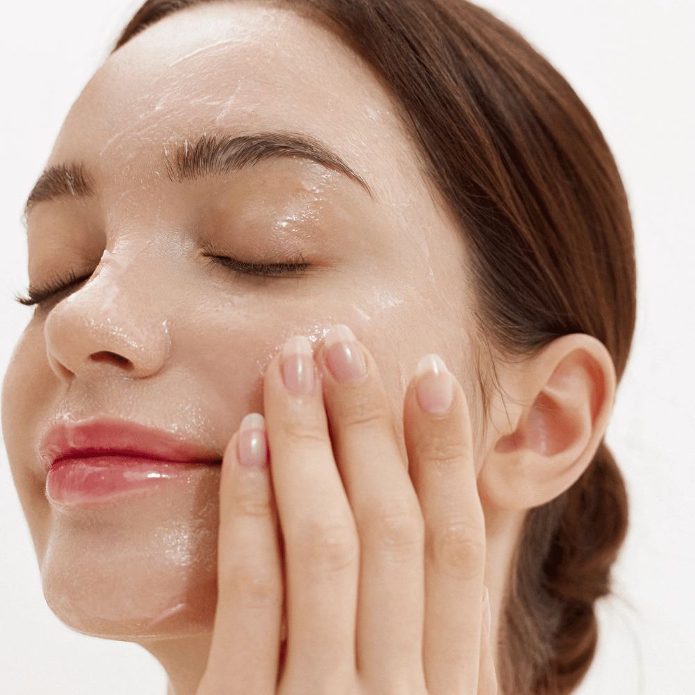 Como Purifying Cleansing Balm aplicado no rosto. Bálsamo cremoso que derrete ao contato com a pele e remove suavemente sujeira, protetor solar e maquiagem.
