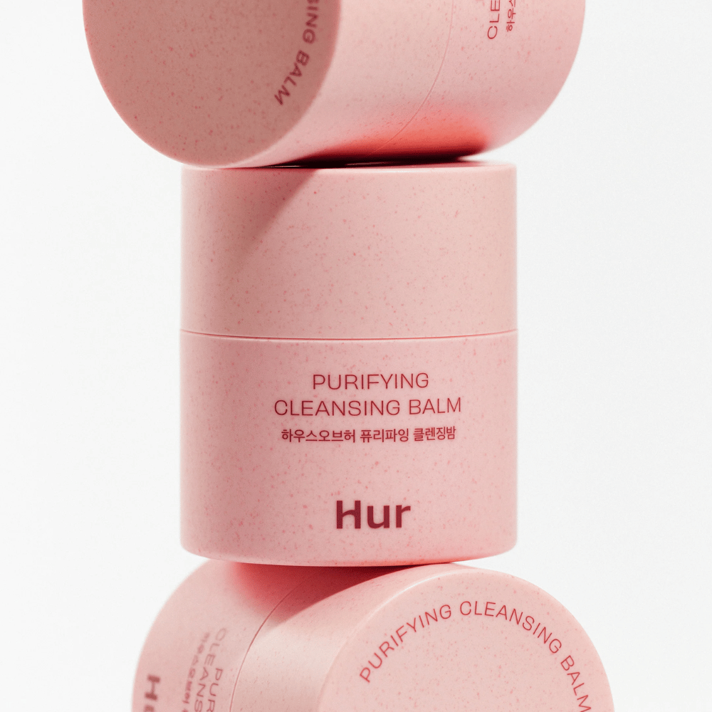 Como Purifying Cleansing Balm em embalagem rosa empilhada no estúdio. Bálsamo de limpeza que dissolve eficazmente maquiagem, sebo e impurezas sem ressecar a pele.