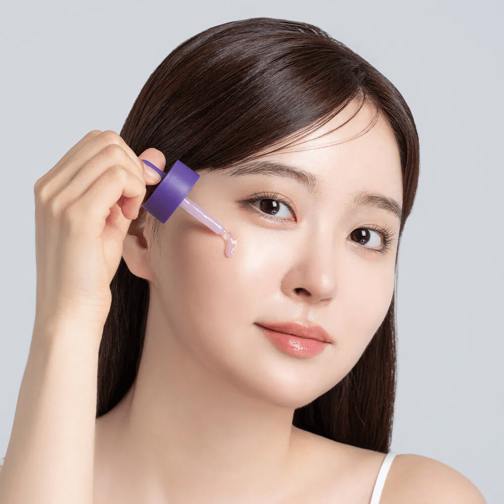 Aplicação de Cellology Purple Carrot Pore Ampoule com conta-gotas no rosto para cuidado dos poros e textura de pele mais uniforme.