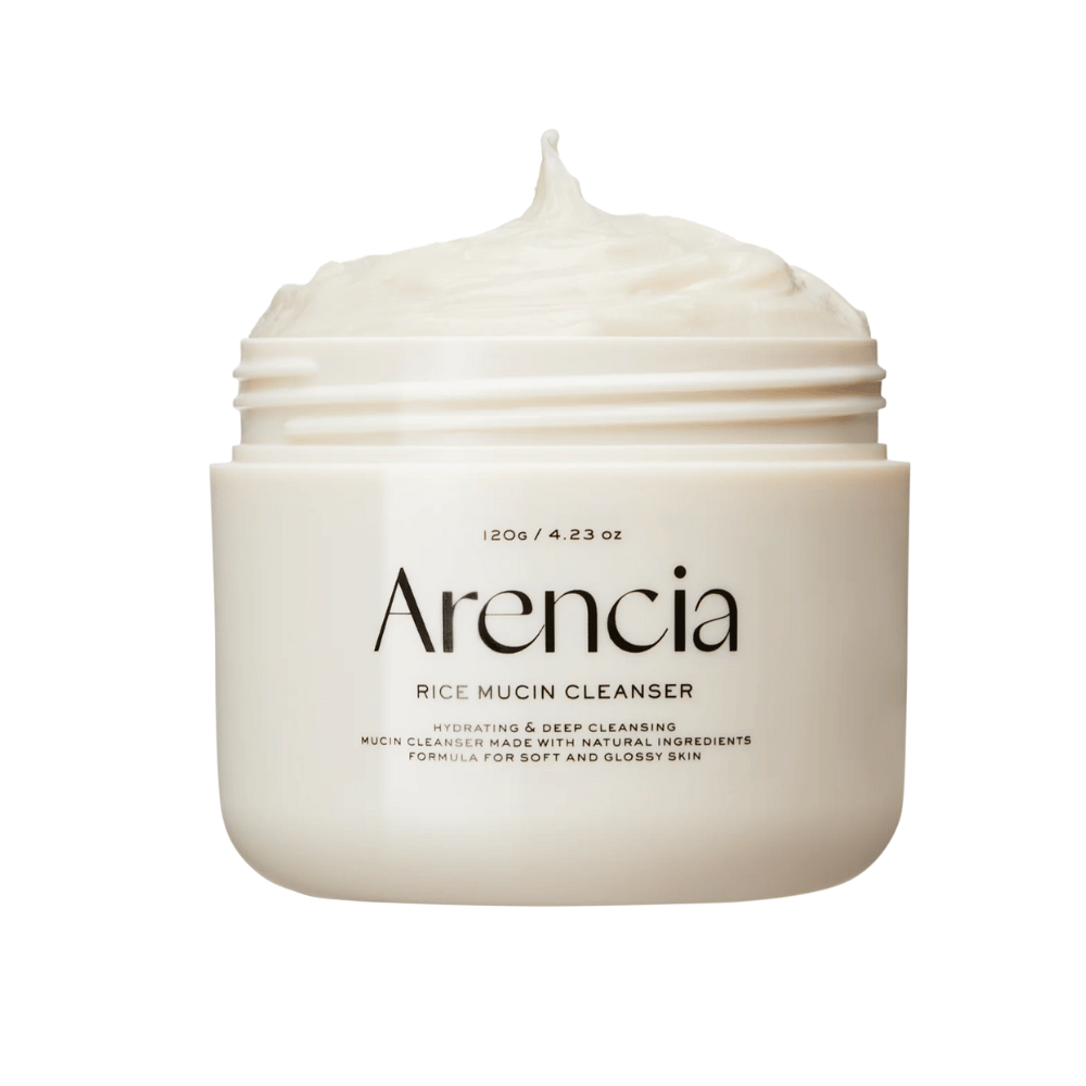 Imagem do produto Arencia Rice Mucin Cleanser em um pote branco com textura cremosa e batida que se projeta da abertura. O texto na embalagem destaca hidratação e limpeza profunda.