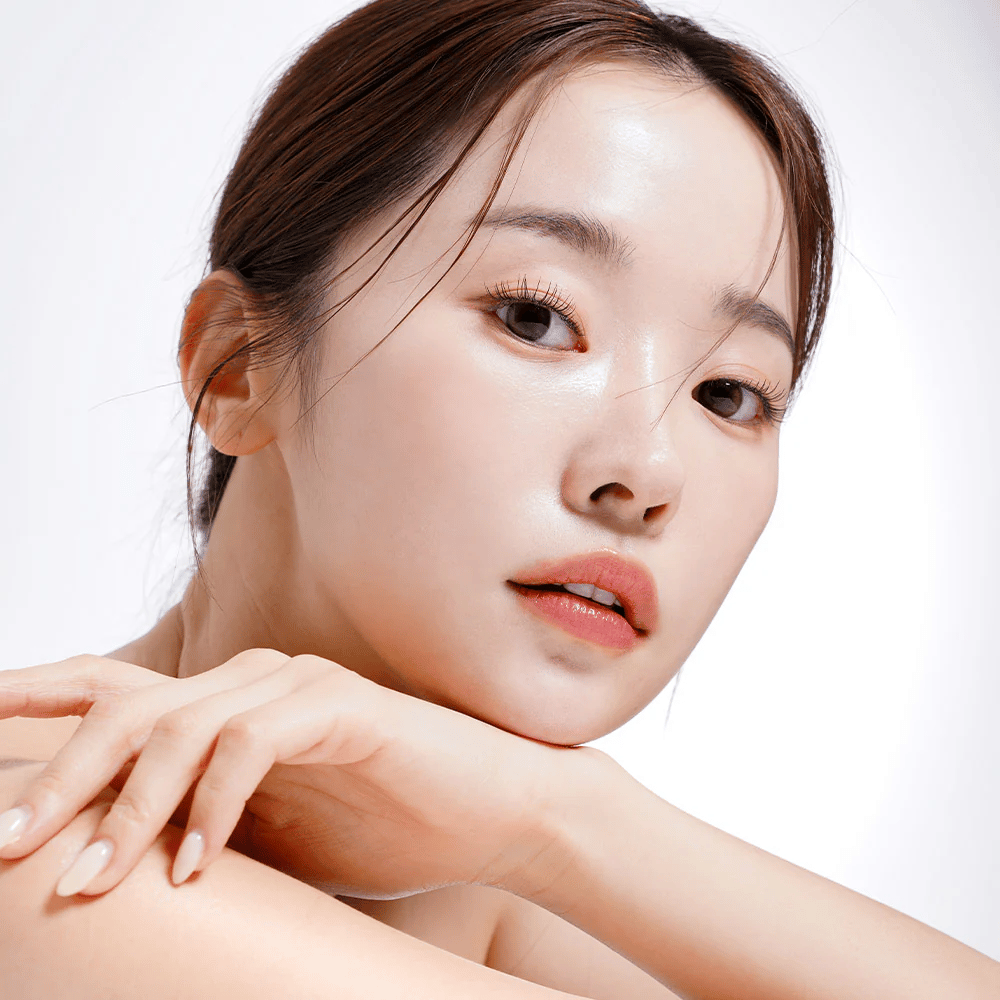 Close-up de uma mulher com pele radiante e hidratada. Sua beleza natural é realçada por uma iluminação suave, proporcionando um visual fresco e saudável.