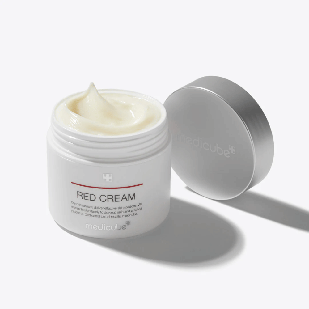 Frasco aberto com medicube Red Cream 50ml – um creme facial amarelo claro em embalagem branca com tampa prateada, desenvolvido para pele propensa a acne.