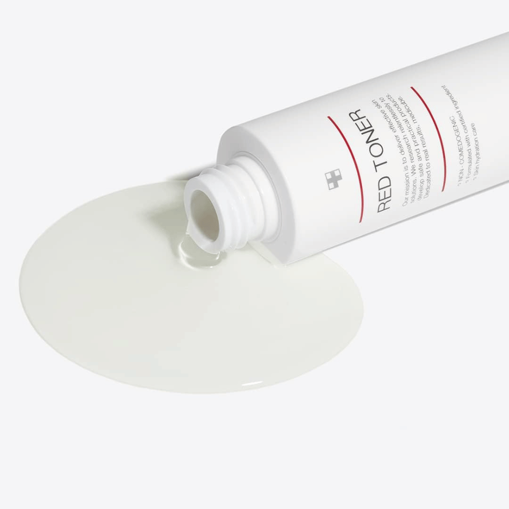 Garrafa aberta com medicube Red Toner sendo derramada em uma superfície branca – mostra a consistência leve e líquida do produto.
