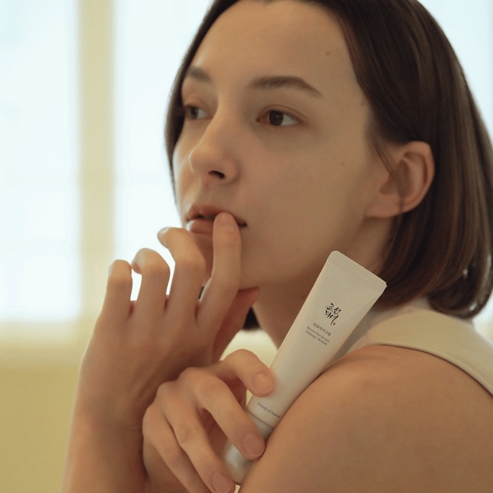 Modelo segura Beauty of Joseon Revive Eye Serum e aplica cuidadosamente na pele para um contorno dos olhos hidratado e suave.