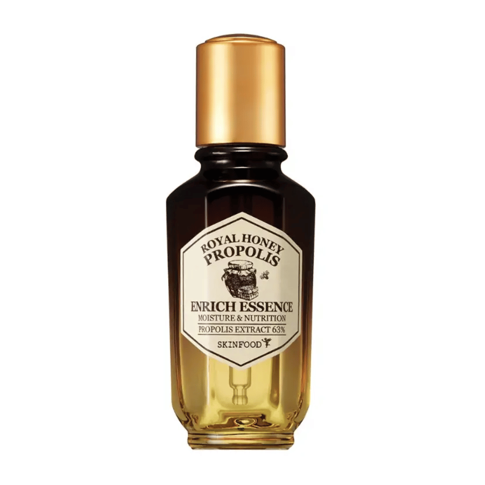 Imagem de uma garrafa de vidro com líquido escuro e tampa dourada. No rótulo da garrafa está escrito "Royal Honey Propolis Enrich Essence" seguido de "Moisture & Nutrition" e "Propolis Extract 63%". A marca "Skinfood" também aparece na parte inferior do rótulo.