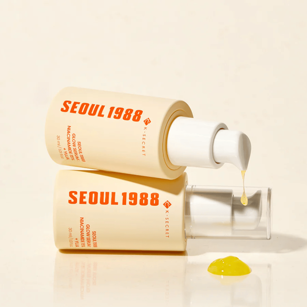 Dois frascos de Seoul 1988 Glow Serum deitados e em pé, com soro amarelo pingando da bomba.
