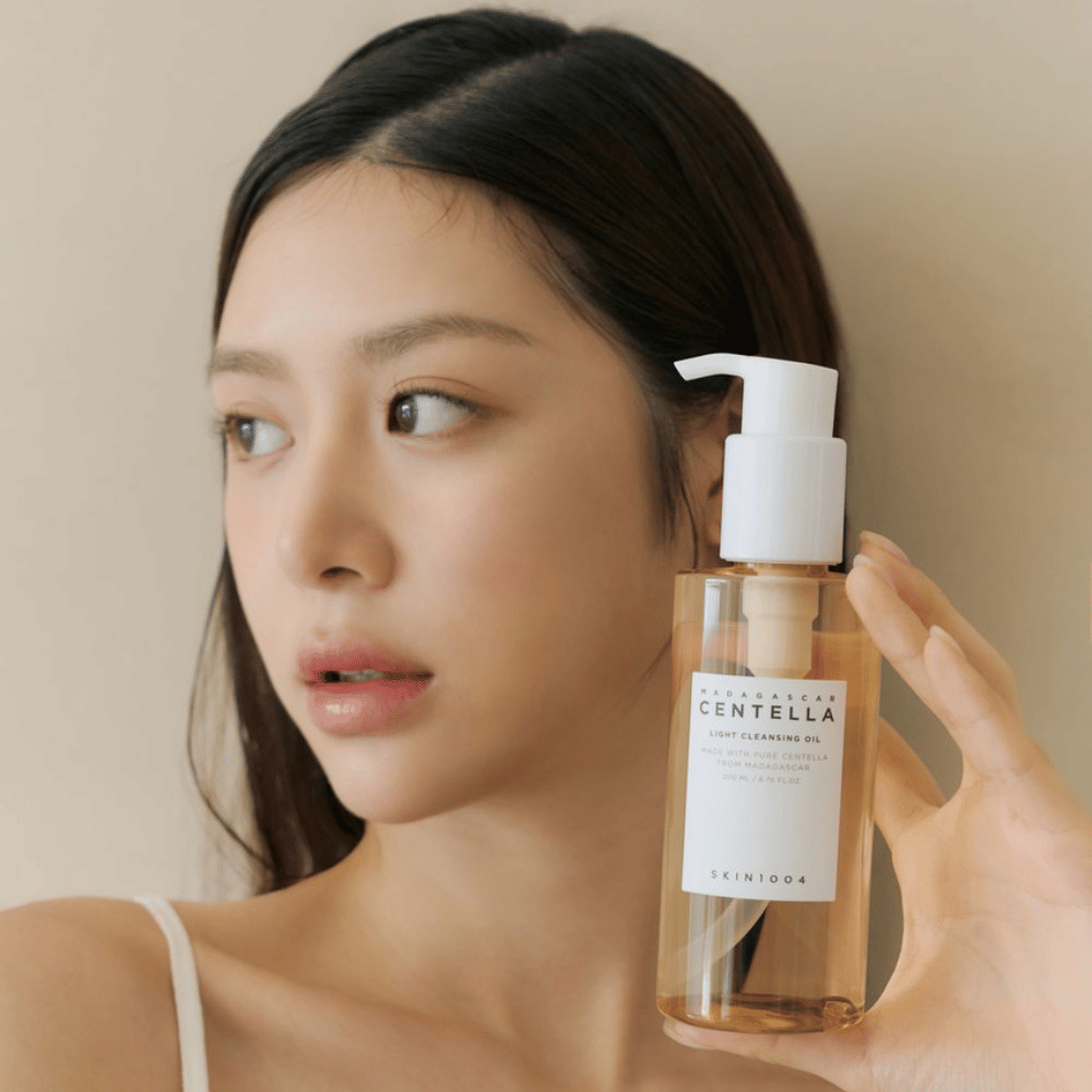 Uma mulher segurando uma garrafa de SKIN1004 Madagascar Centella Light Cleansing Oil 200 ml de limpeza facial.