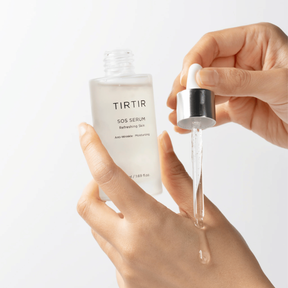 Mãos pingando TIRTIR SOS Serum de uma pipeta, destinada a cuidados de pele.