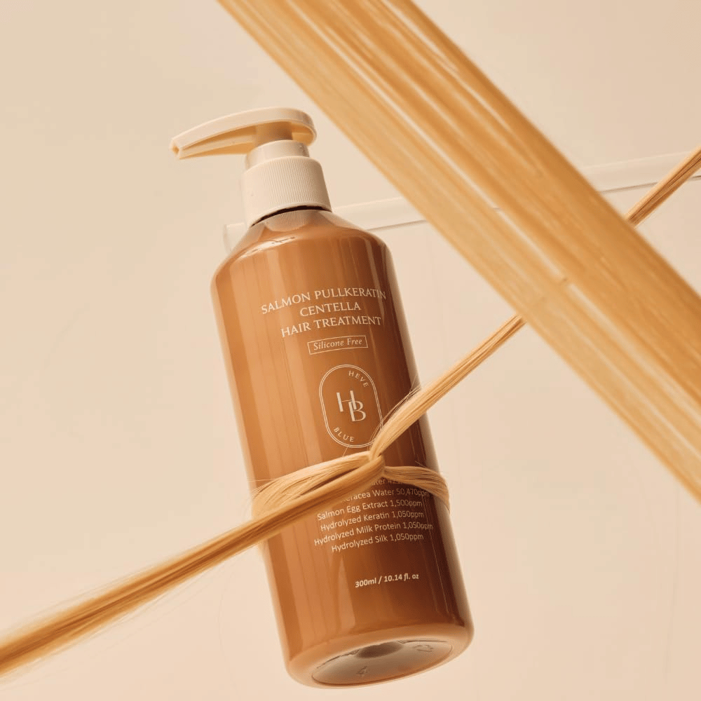 Heveblue Salmon Pullkeratin Centella Hair Treatment em frasco castanho rodeado por madeixas de cabelo. A imagem destaca as propriedades de cuidado do tratamento capilar, com foco no brilho, na força e num cabelo sedoso.